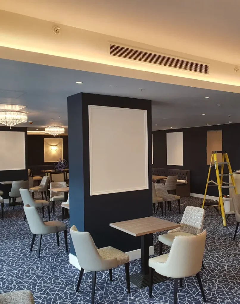 painting and decorating contractors work painting a pub, navy walls with white panels and wooden tables